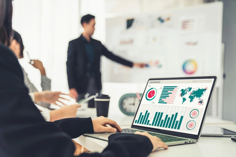 Digitale Analyse und Strategieentwicklung für nachhaltiges Wachstum Mehrere Personen analysieren an einem Laptop mit Dashboard-Daten Kennzahlen und Strategien, während Ergebnisse in einem Workshop präsentiert werden.
