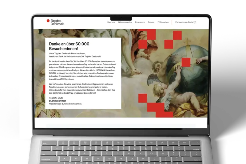 Laptop mit geöffneter Webseite des Tags des Denkmals, gezeigt wird die Startseite mit Dankesbotschaft an über 60.000 Besucher:innen und Hintergrundmotiv eines historischen Gemäldes.