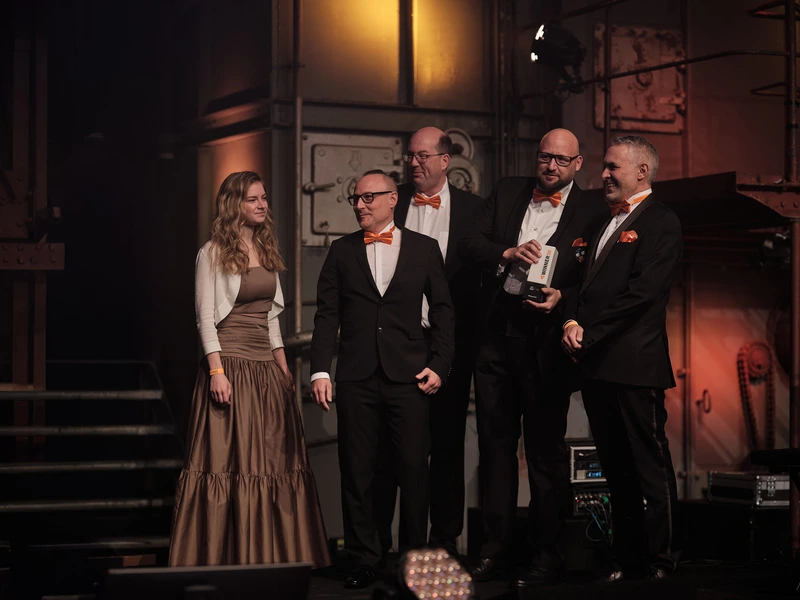 Das Team von Earlybird und +Pluswerk steht während der TYPO3-Preisverleihung auf der Bühne, um den Preis in der Kategorie „Kultur“ entgegenzunehmen. Die Trophäe wird hochgehalten, und es herrscht eine feierliche Stimmung.