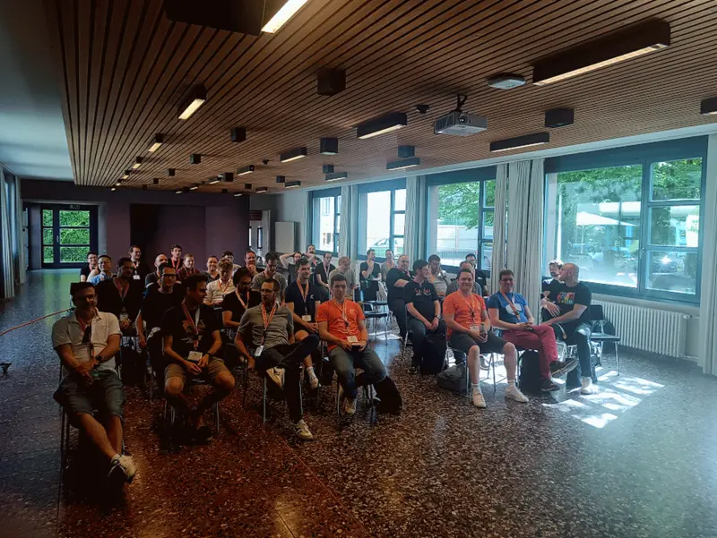 Die TYPO3camp-Community in Zürich Eine Gruppe von etwa 60 Teilnehmern sitzt in einem Raum, schaut in die Kamera und lächelt.