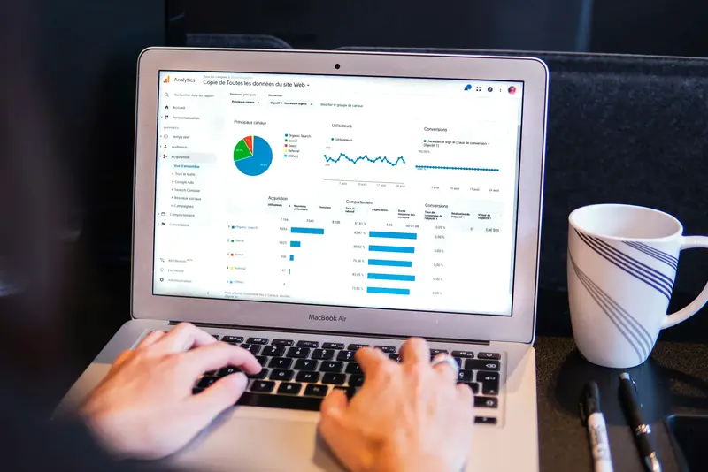 Person working on a laptop, analysing performance data from Google Ads and website campaigns in an analytics dashboard.
