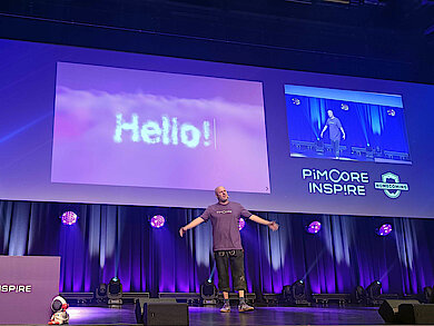 Dietmar Rietsch auf der Bühne beim Opening der Pimcore Inspire 2025, vor großem „Hello!“-Slide und „Homecoming“-Branding