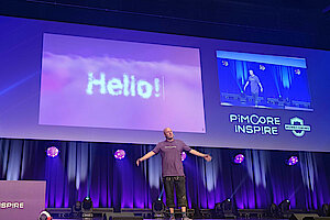 Dietmar Rietsch auf der Bühne beim Opening der Pimcore Inspire 2025, vor großem „Hello!“-Slide und „Homecoming“-Branding