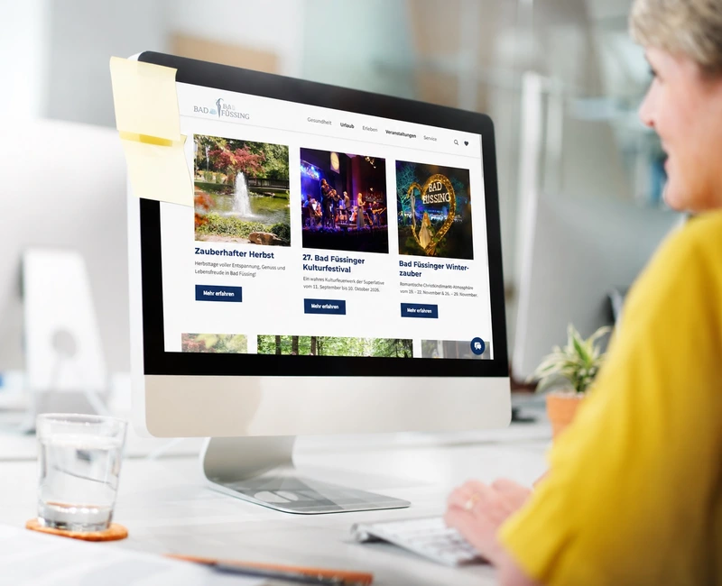 The Bad Füssing website on a desktop monitor, featuring event recommendations and leisure activities.