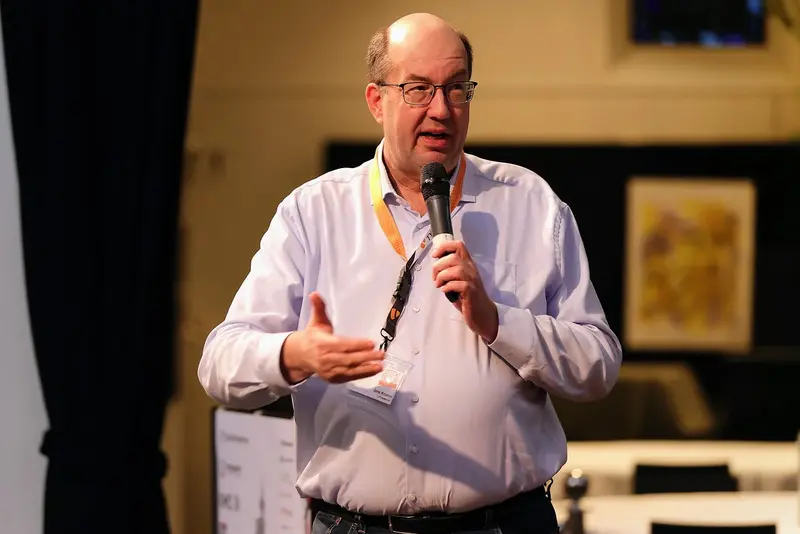 Jens Krumm spricht auf einer TYPO3-Veranstaltung und hält ein Mikrofon in der Hand.