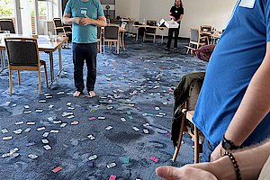 Pluscamp 2023 - agiler Coach Thorsten in Massen von Karten das agilen Kartenspiels Lucky Lachs auf dem Teppichboden