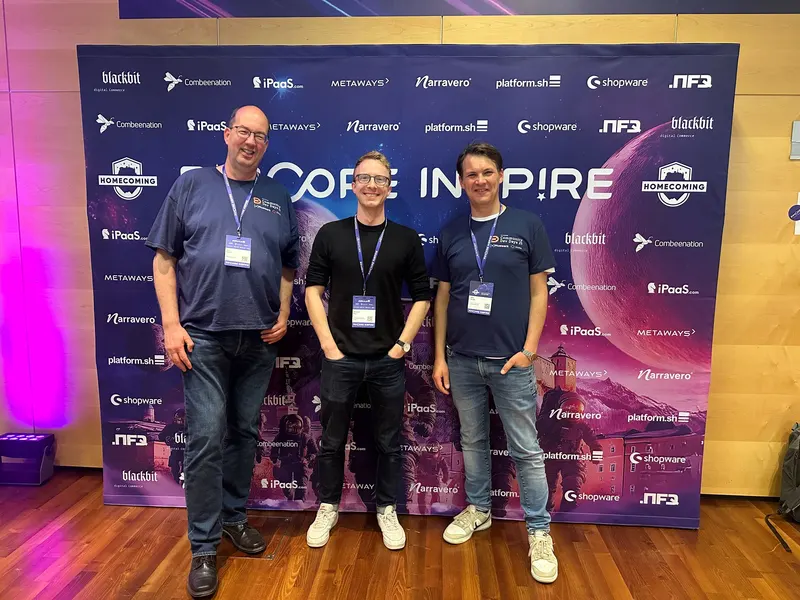 +Pluswerk im Austausch mit Sebastian Maul vom Olympiapark München Jens Krumm, Sebastian Maul (Olympiapark München) und Mike Streibl vor der Sponsorenwand der Pimcore Inspire 2025