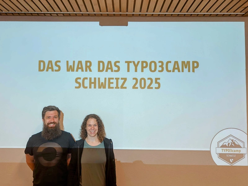 Abschied mit einem Lächeln Zwei Personen stehen vor einer Projektion mit der Aufschrift „Das war das TYPO3camp Schweiz 2025“.
