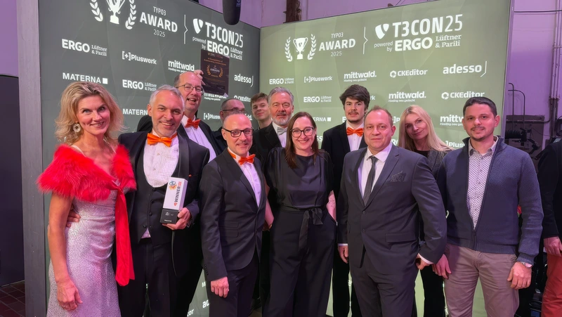 Ein großes Gruppenfoto der Teams von +Pluswerk und Earlybird in Abendgarderobe, die gemeinsam vor der Kulisse des TYPO3-Awards bei der Gala 2025 in Düsseldorf stehen. Mehrere Personen halten die Award-Trophäe in den Händen und lächeln stolz in die Kamera.