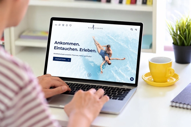 The Bad Füssing website’s homepage displayed on a laptop, featuring a large image of a thermal spa.