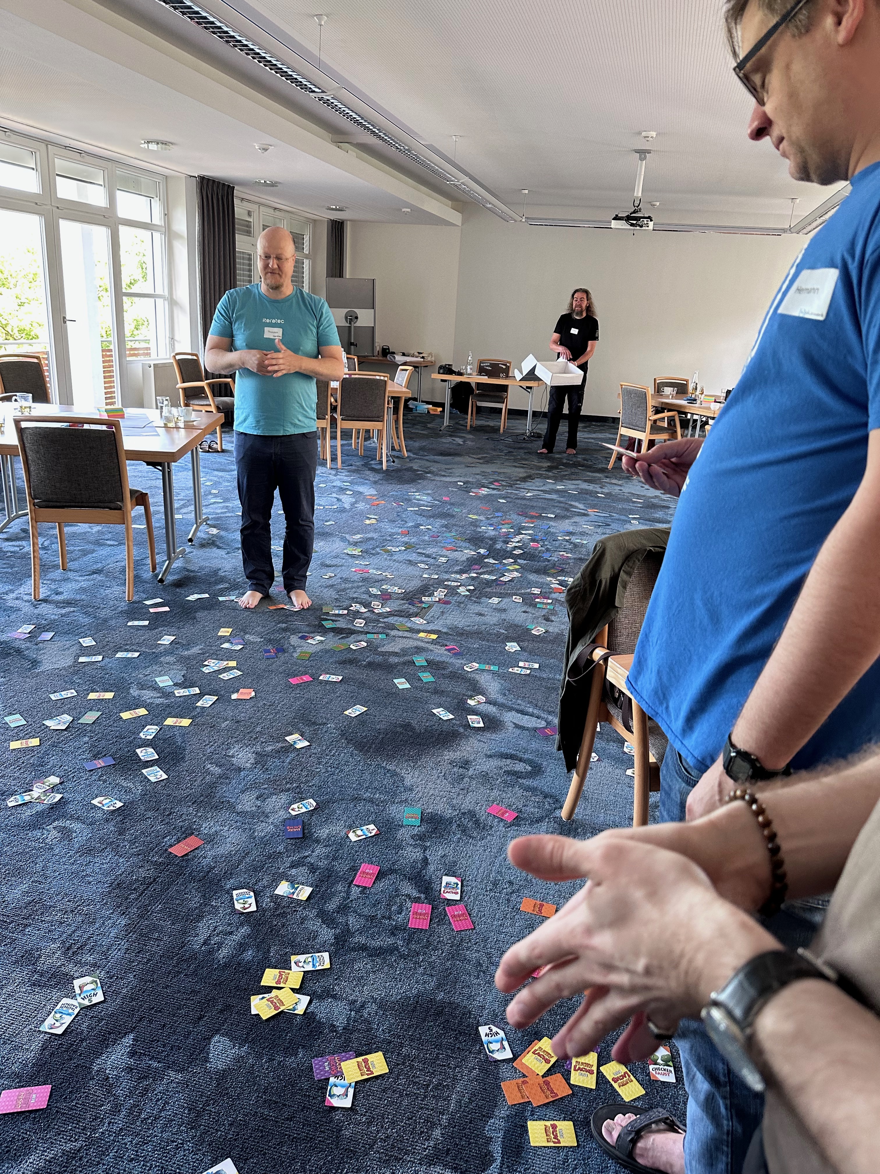 Pluscamp 2023 - agiler Coach Thorsten in Massen von Karten das agilen Kartenspiels Lucky Lachs auf dem Teppichboden